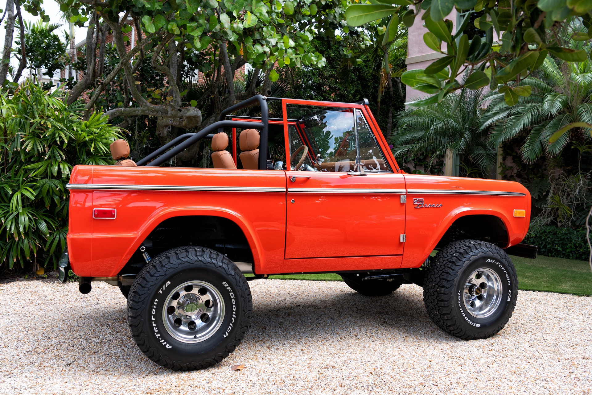 orange red Ford Bronco sport cabriolet tuned car parked under trees
